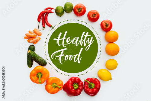 top view of circle of vegetables and fruits with text Healthy Food isolated on white