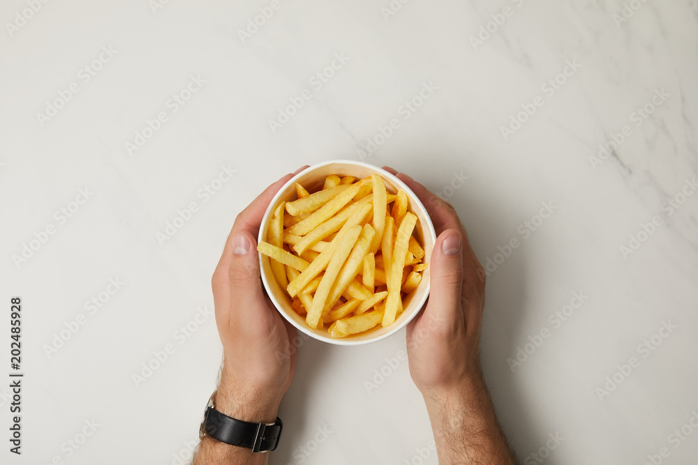 Φωτογραφία cropped shot of man holding bowl of french fries on white