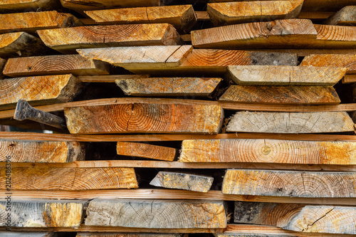 Stack of stacked Lumber. Dried wood boards with a crack. Different types of wood.