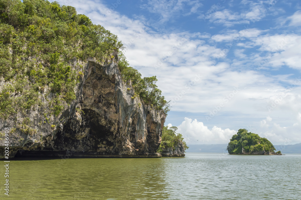 Obraz premium small islands, rocks in the Atlantic Ocean, covered with tropical vegetation, against the sky and clouds, Los Haitises National Park, of Samana Bay, Dominican Republic