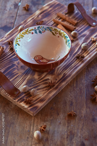 Plate with a bird stands on a wooden tray decorated with cinnamon