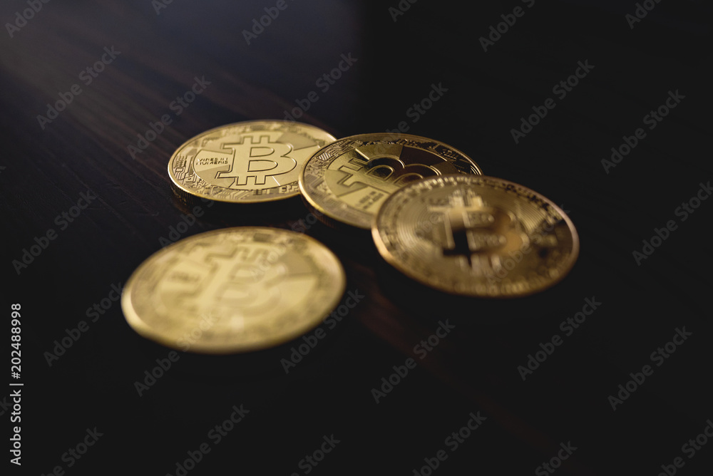 close-up of golden bitcoin coins on wooden table surface close-up of golden bitcoin coins on wooden table surface