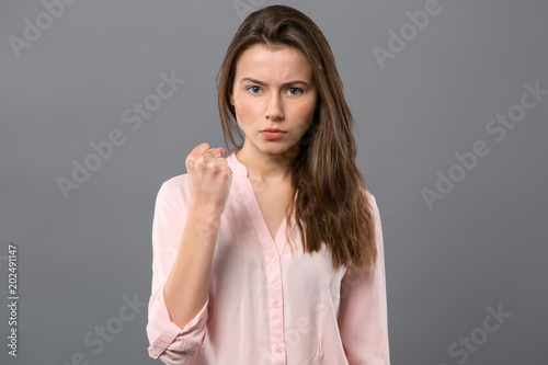 Serious look. Nice serious woman looking at you while showing her fist