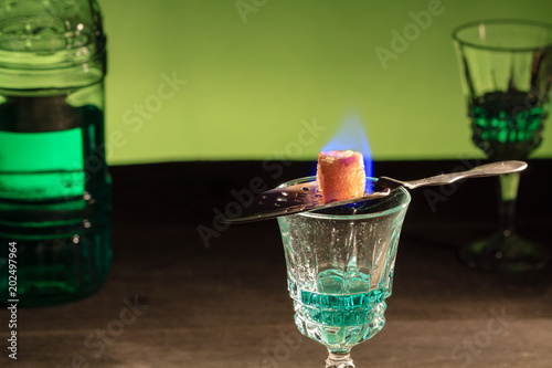 Bottle of absinthe and glasses with burning cube brown sugar. photo