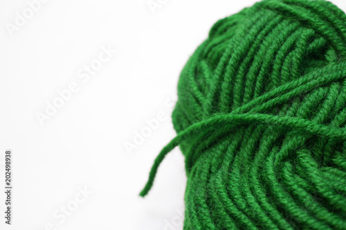 Clew of grassy green knitting wool yarn aside on white surface, handicraft background