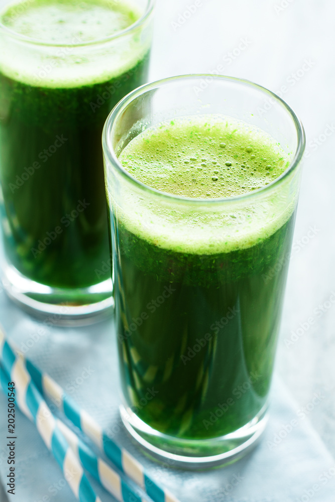 Healthy green smoothie made from spinach, apple and cucumber in a jars with red straw on white wooden table Healthy green smoothie made from spinach, apple and cucumber in a jars with red straw on white wooden table