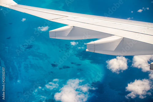 Airplane wing overflying beautiful ocean. Vacation concept