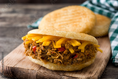 Arepa with shredded beef and cheese on wooden background. Venezuelan typical food

 photo