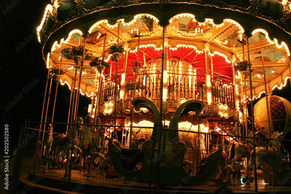 Night fun in Paris street, merry-go-round in the lights attracting tourists with fantasy Night fun in Paris street, merry-go-round in the lights attracting tourists with fantasy
