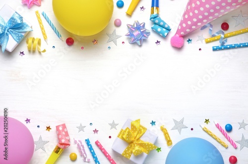 Holiday frame or background with colorful balloon, gift, confetti, silver star, carnival cap and streamer. Flat lay style. Birthday or party greeting card with copy space.