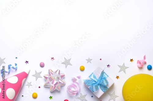 Holiday frame or background with colorful balloon, gift, confetti, silver star, carnival cap and streamer. Flat lay style. Birthday or party greeting card with copy space.