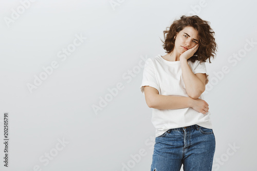 Date ruined with boring stories about ex girlfriend. Bothered displeased attractive caucasian female model with curly hair, leaning head on palm, frowning, being tired and fed up of university photo