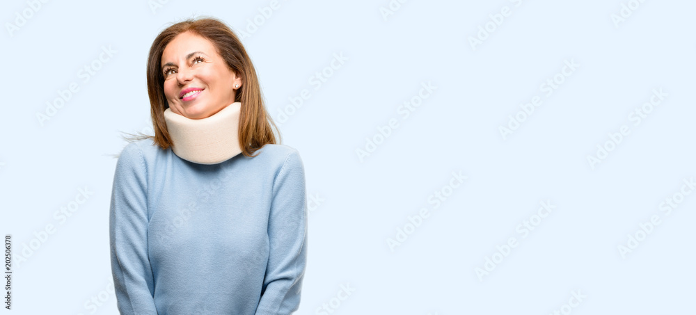Injured woman wearing neck brace collar thinking and looking up expressing doubt and wonder isolated blue background Injured woman wearing neck brace collar thinking and looking up expressing doubt and wonder isolated blue background