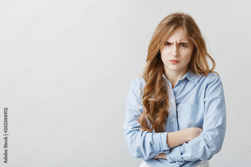 Hate you, do not talk to me. Portrait of offended cute european female with blond hair, holding hands crossed on chest, frowning, being disappointed and sad from insult, standing over gray wall Hate you, do not talk to me. Portrait of offended cute european female with blond hair, holding hands crossed on chest, frowning, being disappointed and sad from insult, standing over gray wall