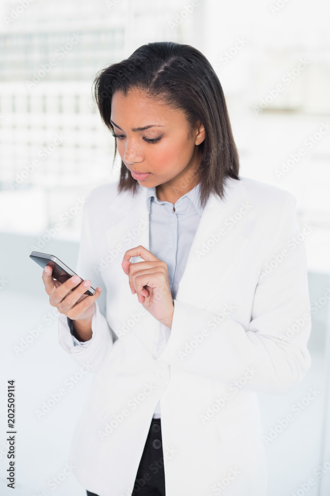 Thinking young dark haired businesswoman looking at her mobile phone Thinking young dark haired businesswoman looking at her mobile phone