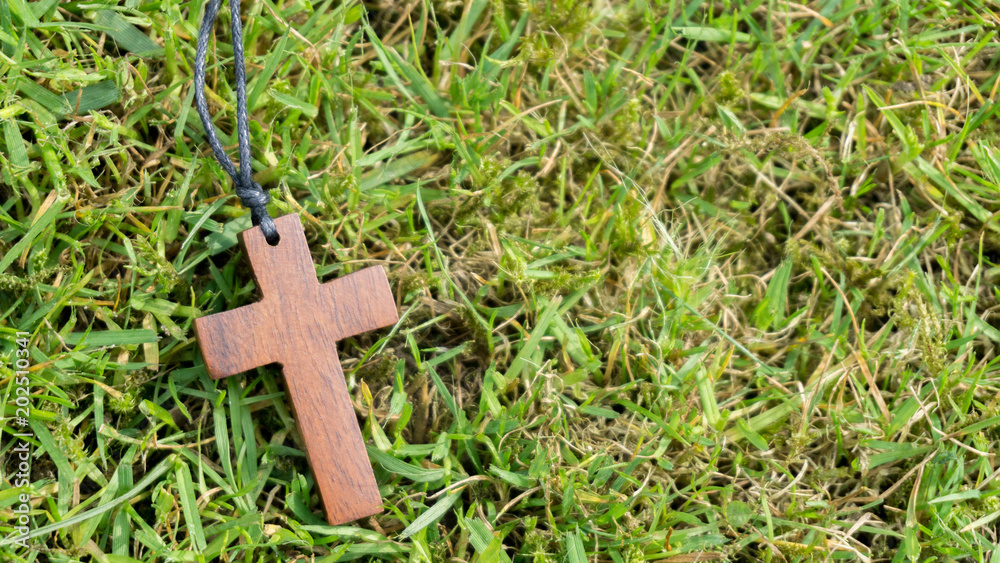 brauner Holzkreuz Anhänger liegt auf dem Rasen brauner Holzkreuz Anhänger liegt auf dem Rasen