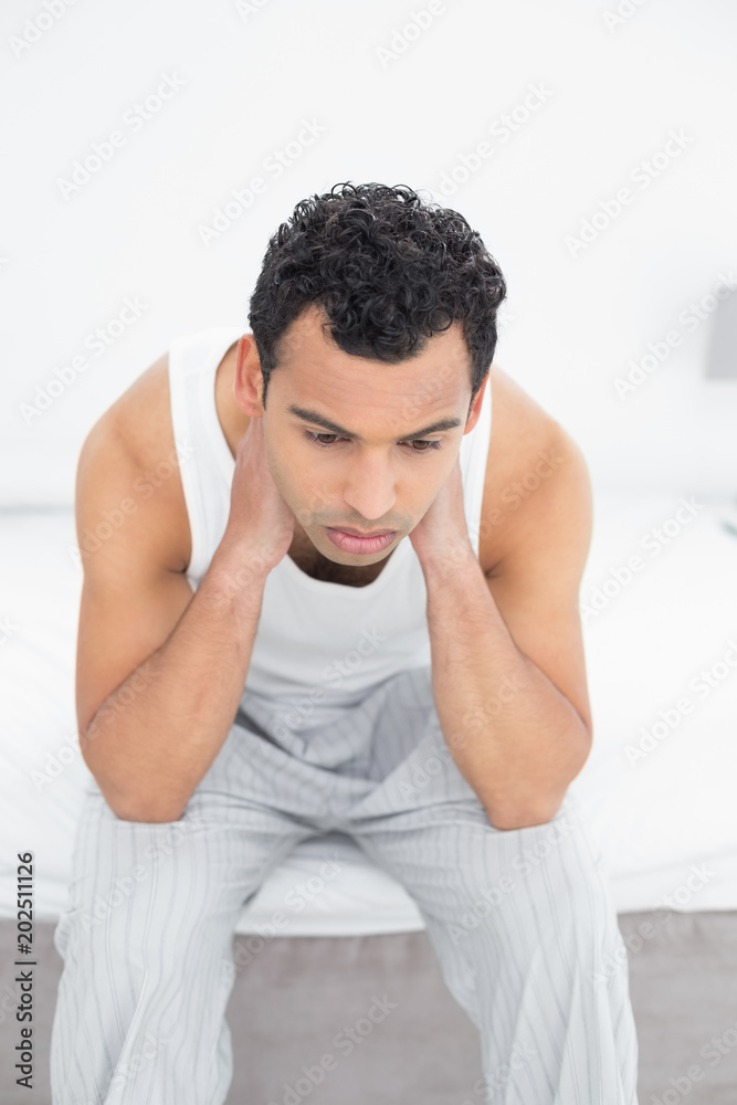 Thoughtful young man sitting on bed Thoughtful young man sitting on bed