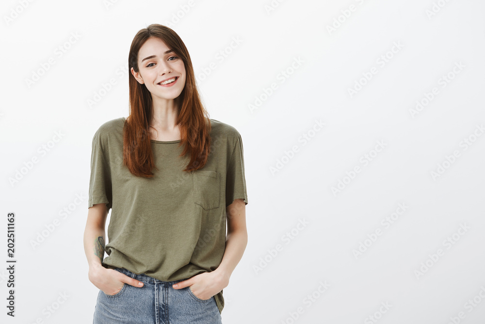 How may I help you. Portrait of friendly confident attractive lifestyle blogger in casual dark-green shirt, holding hands in pockets, standing over gray background and smiling positively How may I help you. Portrait of friendly confident attractive lifestyle blogger in casual dark-green shirt, holding hands in pockets, standing over gray background and smiling positively