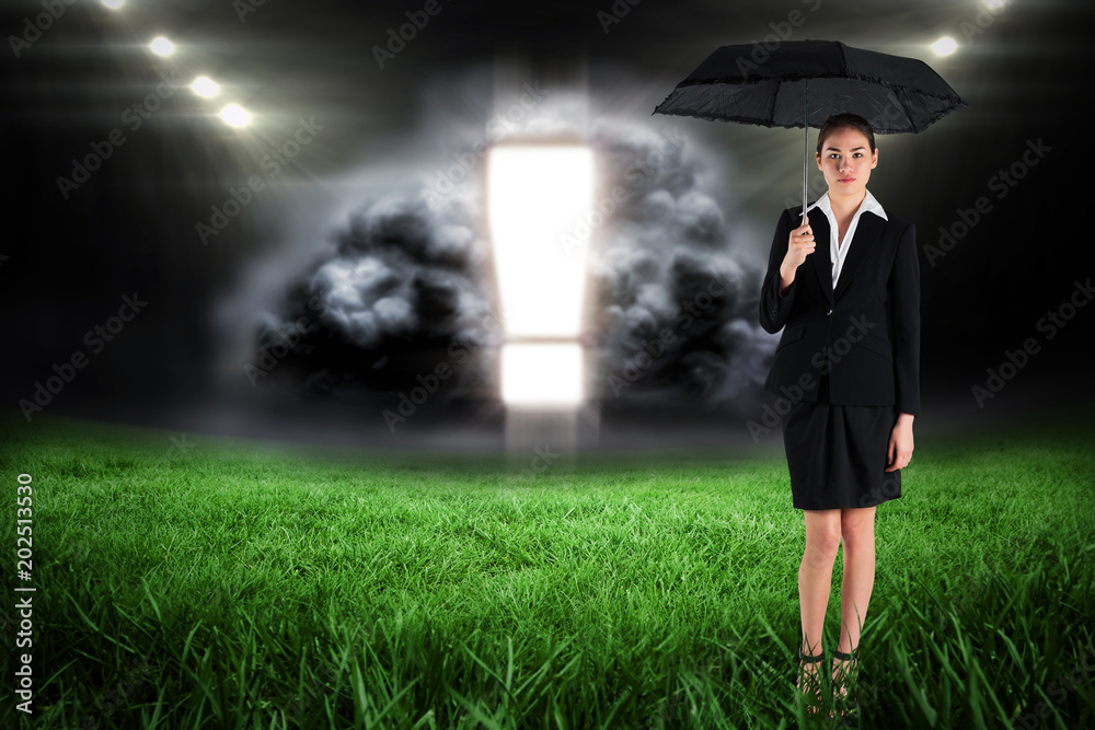 Φωτογραφία Young businesswoman holding umbrella against football pitch with bright lights