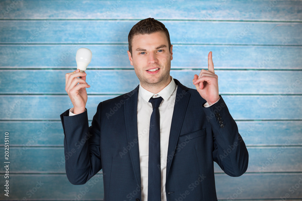 Businessman holding light bulb and pointing against wooden planks Businessman holding light bulb and pointing against wooden planks