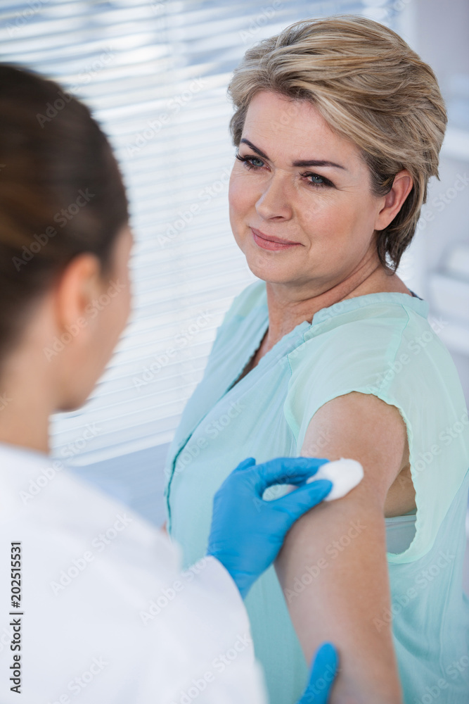 Doctor rubbing patient arm from cotton before injection Doctor rubbing patient arm from cotton before injection