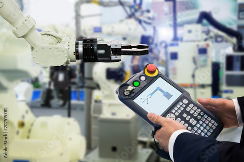 Engineer with teach pendant device. Programming robot with robotic arm. Smart factory 