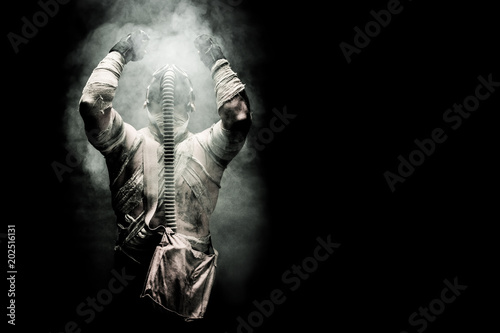 Fototapeta Naklejka Na Ścianę i Meble -  bandaged men in the gas mask on the black background surrounded by smoke and looking at the sky, survival soldier after apocalypse.