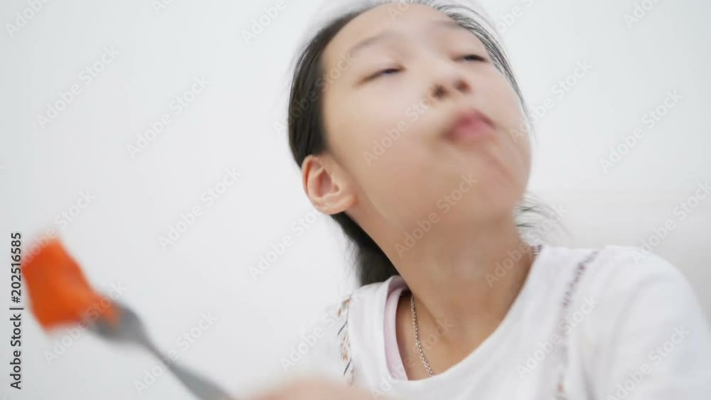 Happy Asian girl sitting on sofa and eating sliced ripe papaya at home. Happy Asian girl sitting on sofa and eating sliced ripe papaya at home.