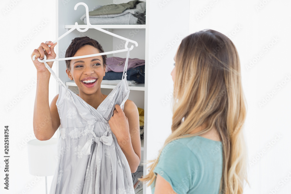 Fototapeta premium Cheerful woman showing a dress to her friend