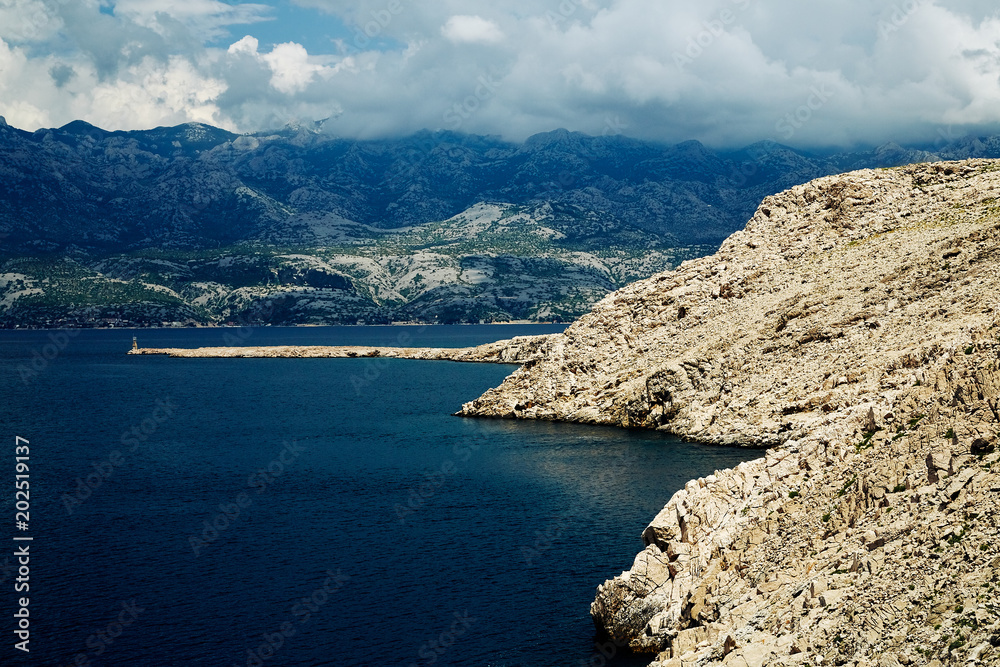 Rocky coast of the central part of Croatia. White clouds in the sky and blue sea.