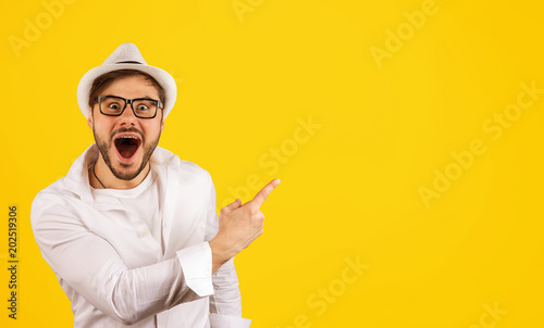 Happy hipster pointing up on yellow