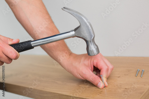 Hands hammering nail in wooden bench