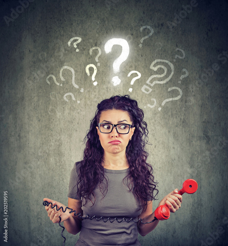 Fotografie Upset worried confused woman with telephone has many questions