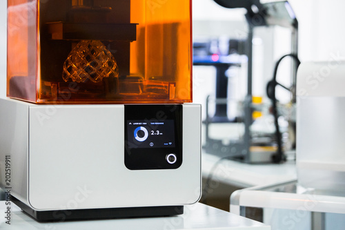 A stereolithography 3d printer in the laboratory prints a structure from a photopolymer.  On the display the process indicator and the number of layers. Creating scaled model by UV polymerization. photo