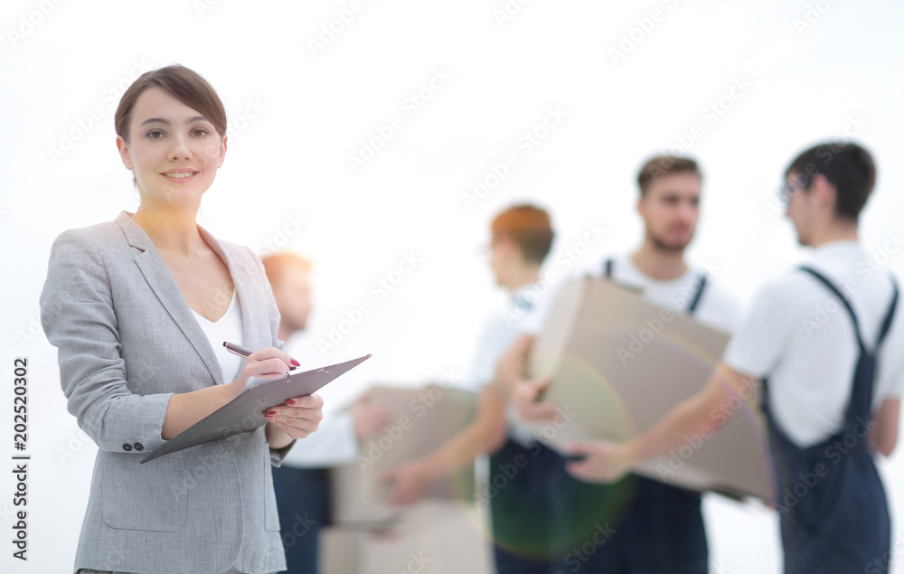 Woman manager holding clipboard on blurred background with mover Woman manager holding clipboard on blurred background with mover