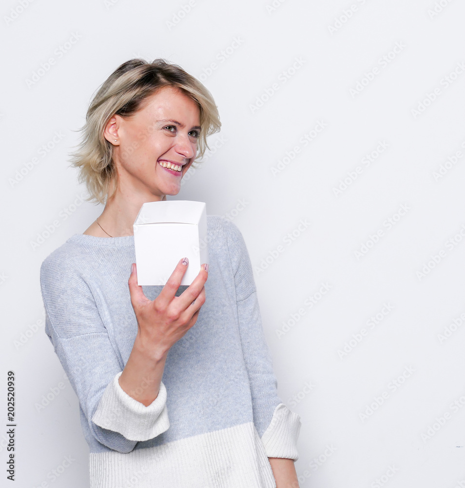 Happy girl with small white gift box. Small gift in the hands of a woman indoor. Happy girl with small white gift box. Small gift in the hands of a woman indoor.