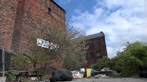 Makeshift garden and rubbish between abandoned  brick warehouse buildings at Liverpool docks.