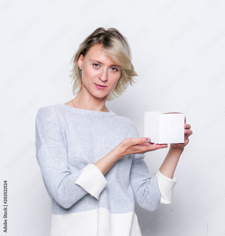 Happy girl with small white gift box. Small gift in the hands of a woman indoor. Happy girl with small white gift box. Small gift in the hands of a woman indoor.