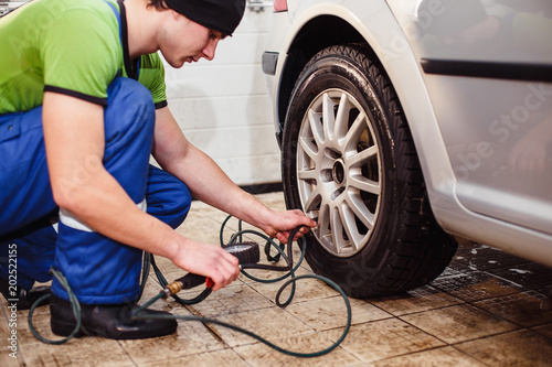 car repair at a service station. A young man checks the tire pressure