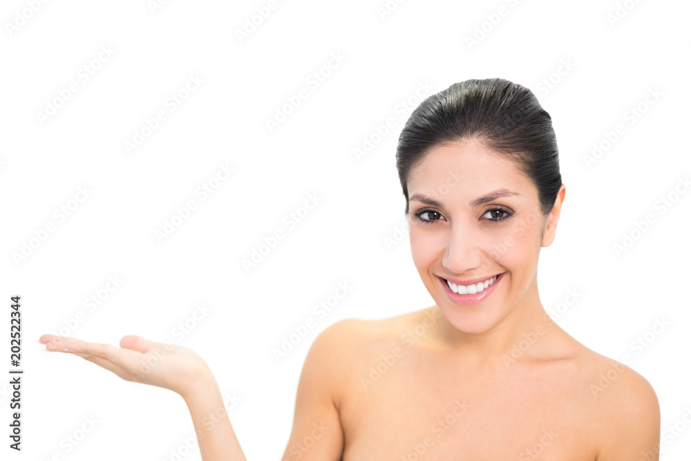 Smiling brunette presenting with hand looking at camera Smiling brunette presenting with hand looking at camera
