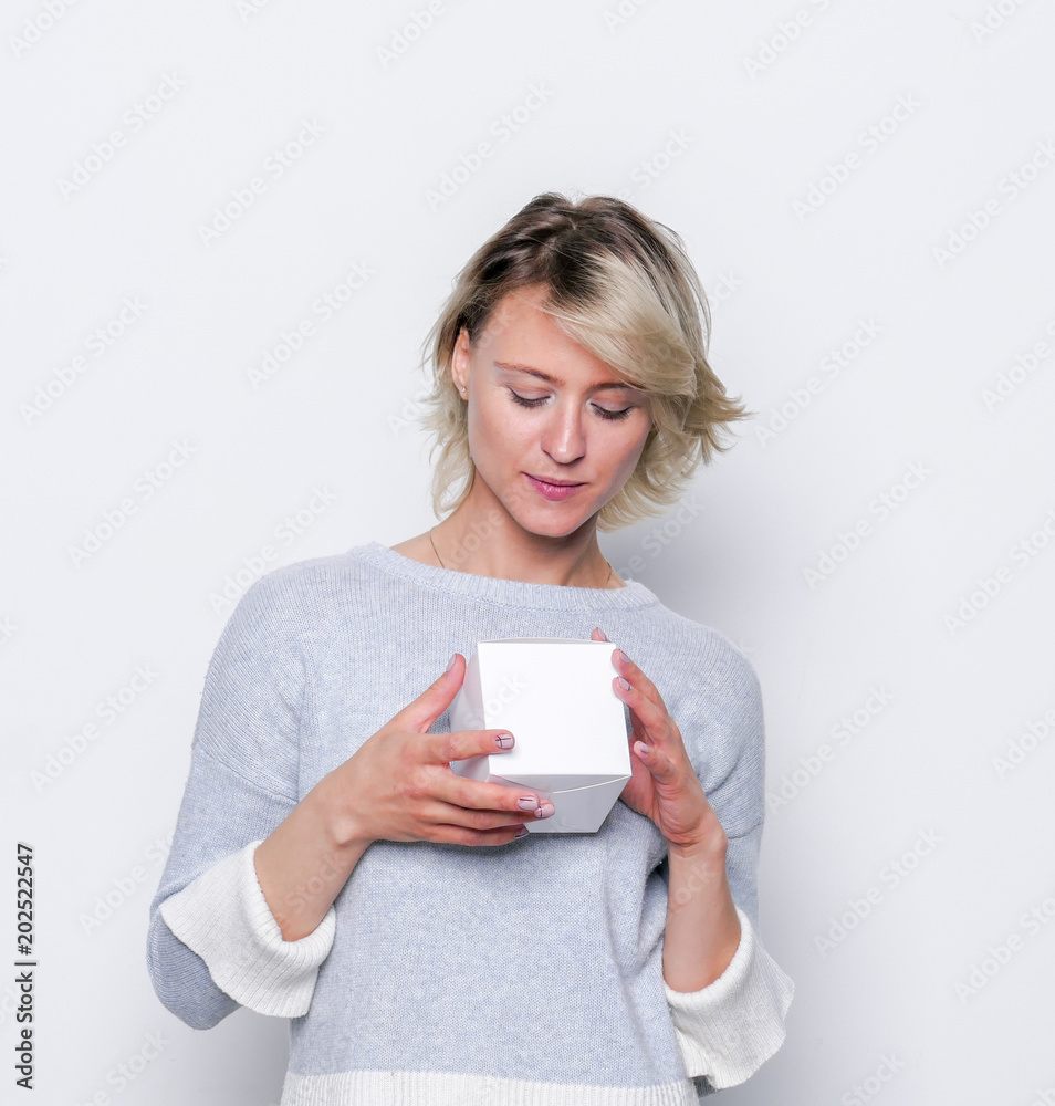 Happy girl giving small white gift box. Small gift in the hands of a woman indoor. Happy girl giving small white gift box. Small gift in the hands of a woman indoor.