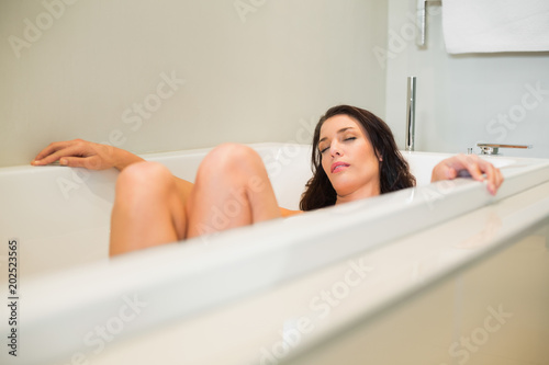 Peaceful natural brown haired woman relaxing in a bathtub
