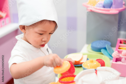 A little chef is playing a food and tea pot toy.