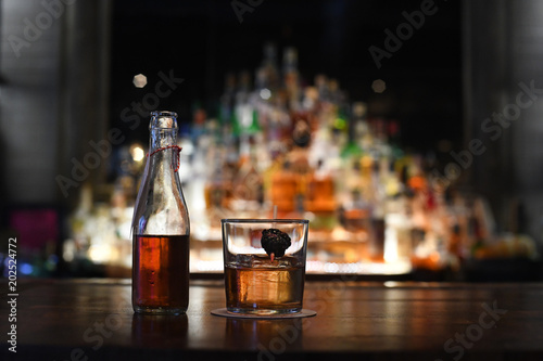 Cocktail and bottle on bar counter