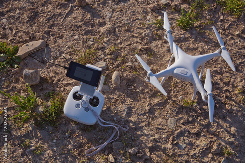 Top view of a flying white professional quadcopter drone camera with green grass in background, aerial photographer equipment, aircraft, rc, remote controller, transmitter . amera Grass preparing photo