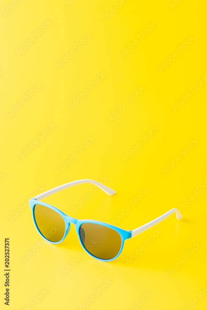 A minimalist arrangement of blue sunglasses on a bright yellow background A minimalist arrangement of blue sunglasses on a bright yellow background