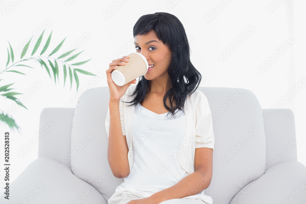 Peaceful black haired woman in white clothes drinking a beverage Peaceful black haired woman in white clothes drinking a beverage