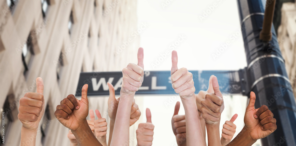 Hands showing thumbs up against wall street