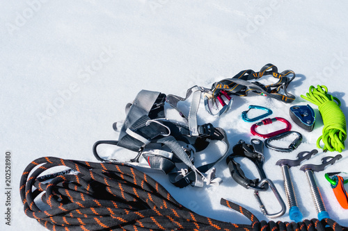 Close-up of winter climbing equipment on fresh snow on a sunny day. Carbines with a rope gazebo and zhumar as well as other adaptations when practicing winter mountaineering. Year-round ascents to photo