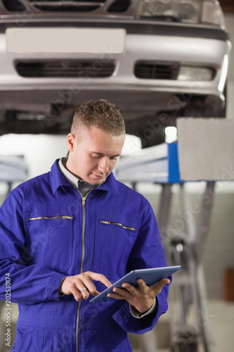 Concentrated mechanic holding a tablet computer